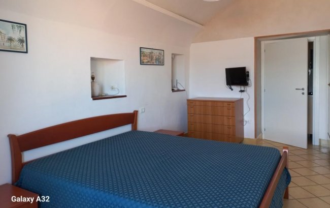 Camera con letto matrimoniale, cassettiera e televisore.