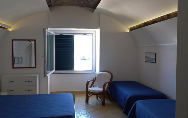 Camera con letti blu e finestra aperta.