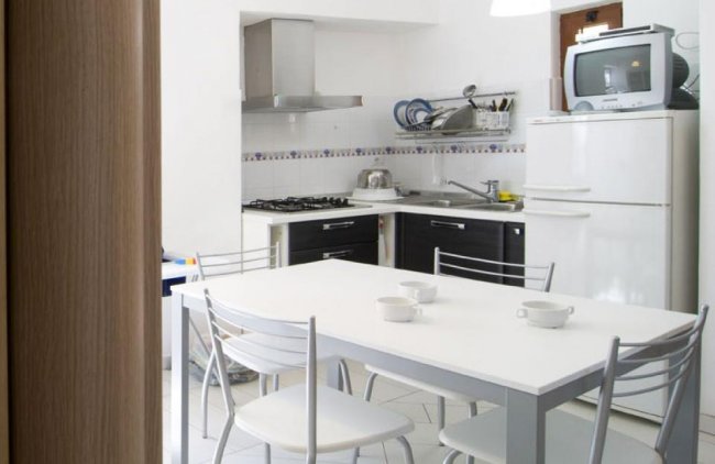 Cucina moderna con tavolo e sedie bianche.