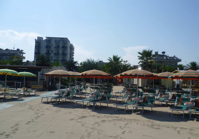 Spiaggia con lettini e ombrelloni colorati.