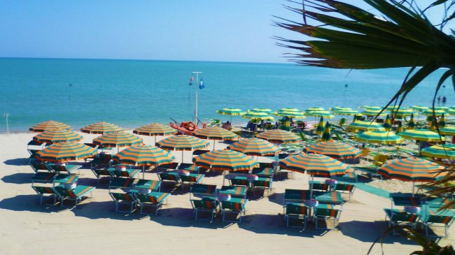 Una spiaggia con lettini e ombrelloni colorati.