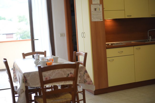 Cucina con tavolo apparecchiato e mobili gialli.