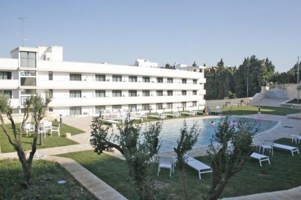 Edificio bianco con piscina e lettini.