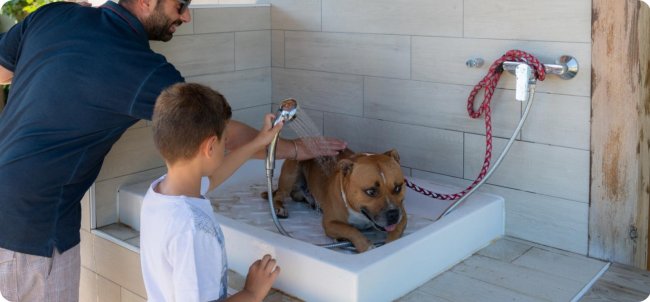 Cane in una vasca, lavato da un uomo e un bambino.