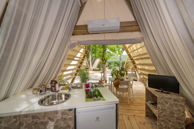 Interno di una tenda glamping con tavolo e sedie all'aperto.