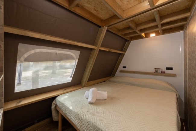 Camera da letto compatta con letto matrimoniale e finestra.