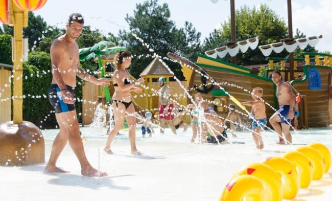 Persone giocano con spruzzi d'acqua vicino a un tema navale.