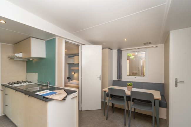 Zona pranzo con tavolo, sedie e cucina.