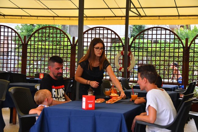 Famiglia servita al tavolo di un ristorante all'aperto.