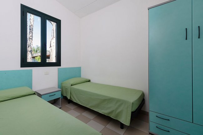 Camera con due letti singoli verdi e armadio.