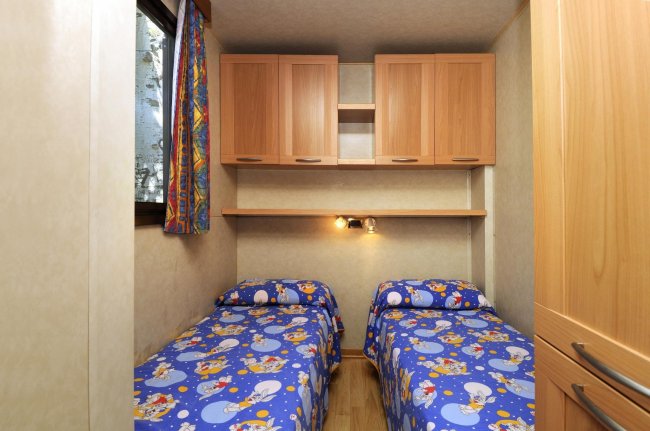 Camera con due letti singoli e lenzuola blu.