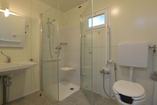 Bagno moderno con doccia e accessori bianchi.