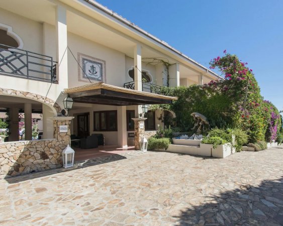 Ingresso di un edificio con pietra, vegetazione rigogliosa e lanterne decorative.