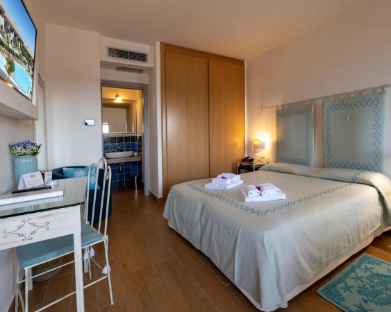 Camera da letto luminosa con letto matrimoniale, scrivania e bagno annesso.