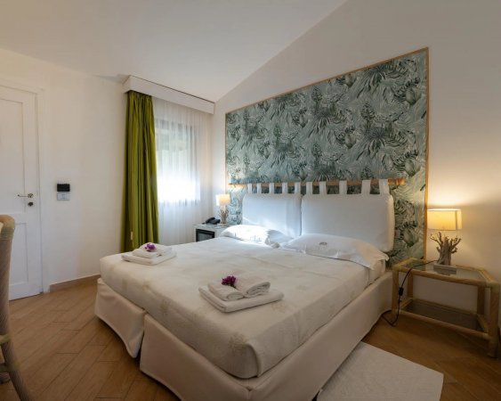 Camera matrimoniale con parete verde e lampade accese.