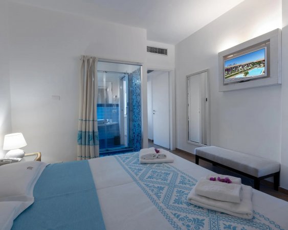 Camera con letto matrimoniale, una TV, bagno privato e luce soffusa.