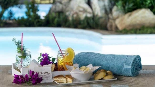 Vassoio con drink, biscotti e tovaglia blu a bordo piscina.