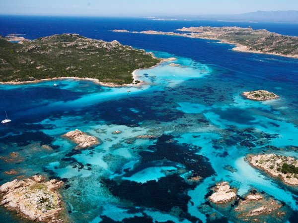Vista aerea di un'area costiera con acque turchesi e isole rocciose verdi.