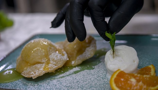 Dolce su piatto blu con decorazioni di arancia e crema.