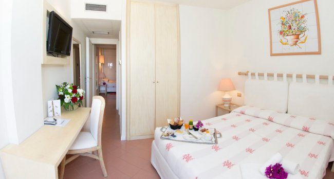 Camera d'albergo luminosa con letto matrimoniale e scrivania.