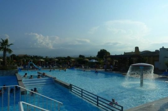 Piscina all'aperto con scivoli e persone che nuotano.
