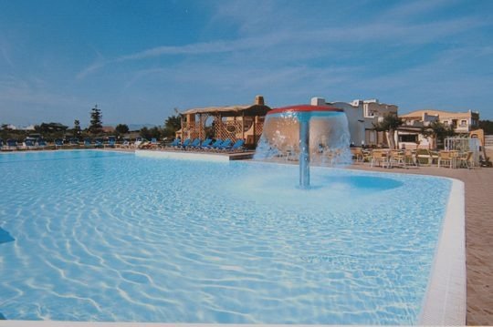 Piscina con getto d'acqua a fungo e lettini.