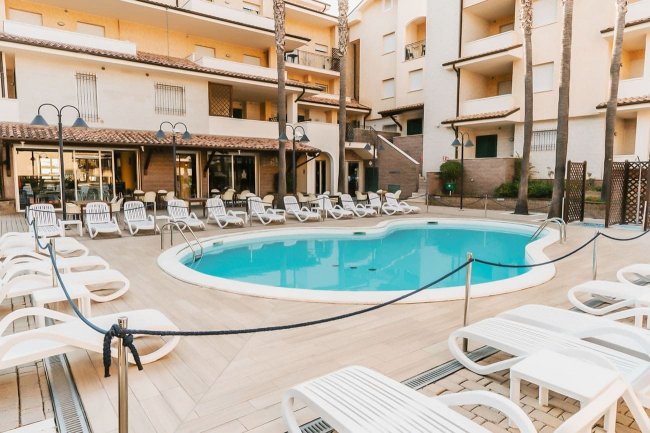 Piscina circondata da lettini bianchi.