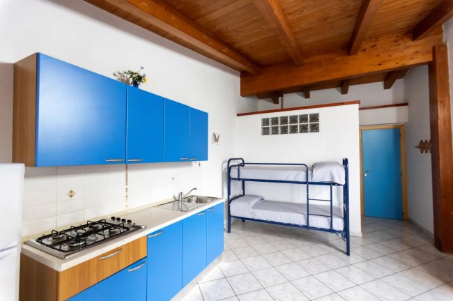 Cucina con armadietti blu e letti a castello.