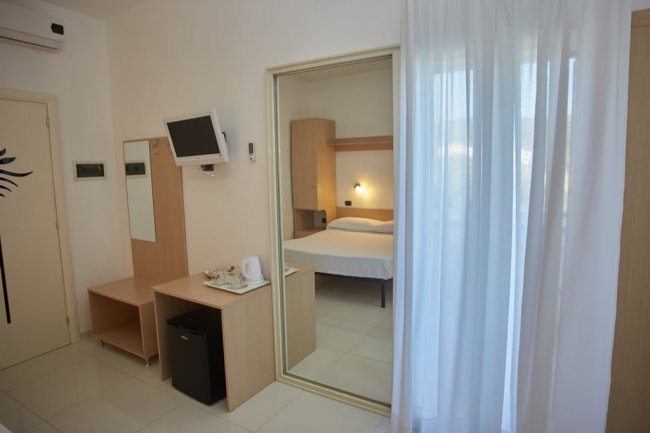 Camera con letto, specchio e TV a parete.