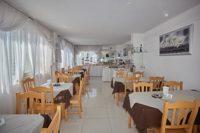 Sala da pranzo con tavoli apparecchiati.