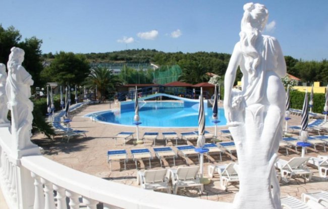 Piscina circondata da statue e lettini.