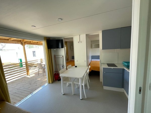 Sala con cucina, tavolo bianco e accesso a terrazza esterna.