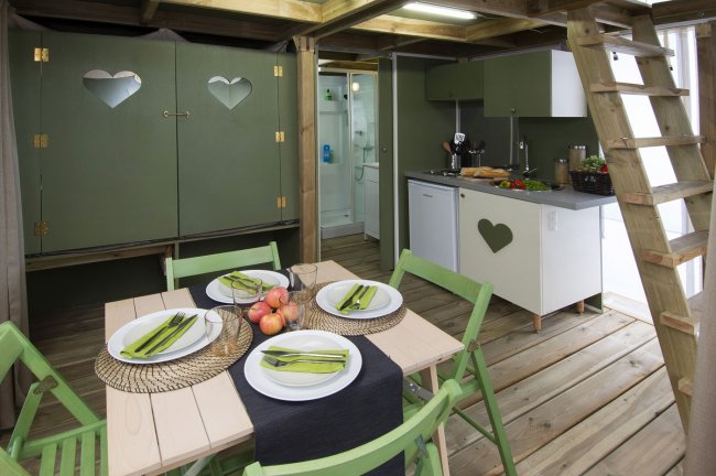 Una cucina rustica con tavolo apparecchiato e mobili verdi.