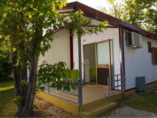 Casa mobile con piccolo portico e alberi intorno.