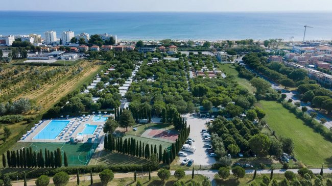 Vista aerea di un complesso turistico con piscina vicino al mare.