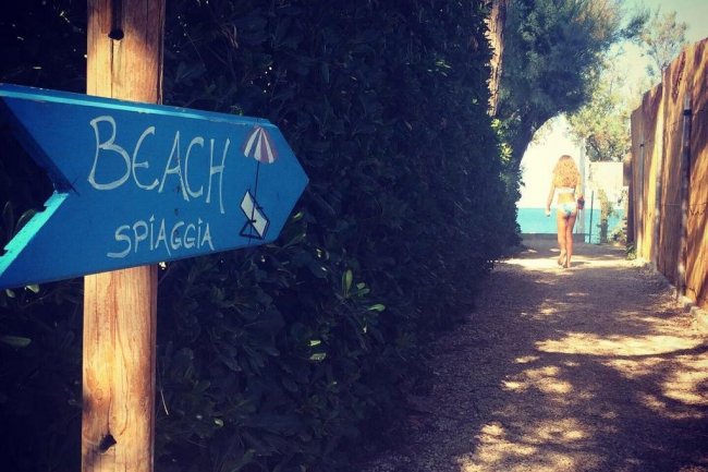 Cartello verso la spiaggia, donna in costume.