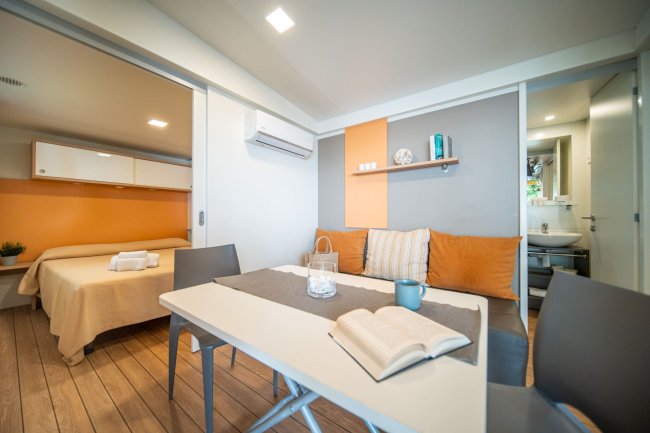 Salotto accogliente con tavolo e cucina a vista.